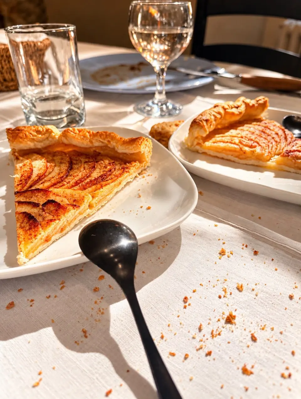 Parts de tarte fine aux pommes au soleil, sur une nappe blanche